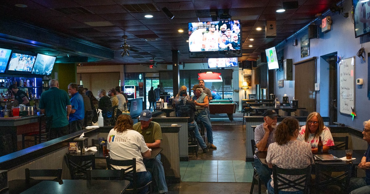 Interior, patrons seated in a dining area and along a bar counter