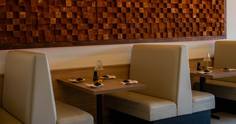 Interior of a restaurant featuring two light-colored booths, a wooden table with items