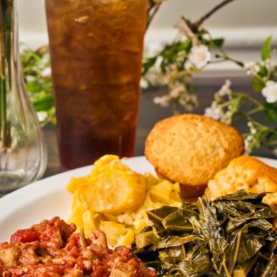Platter of sides featuring okra and tomatoes, collard greens, and a muffin.