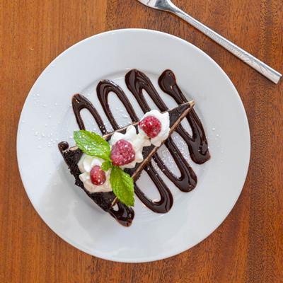 Hazelnut Cream Chocolate Cake, topped with whipped cream and raspberries.
