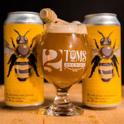 Two yellow cans with a printed bee and a glass of drink.