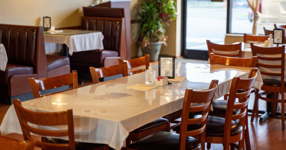 Cozy restaurant interior with wooden chairs and tables covered in white tablecloths
