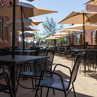 Sunny patio with tables chairs and tan umbrellas.