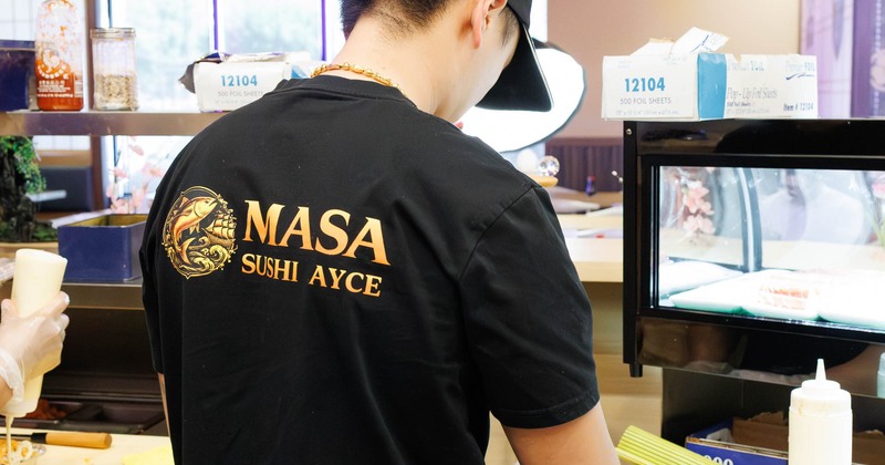 Staff member wearing a black branded t-shirt while working behind a counter