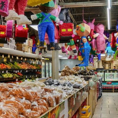 Supermarket interior with packaged goods, fresh produce, and colorful pinatas.