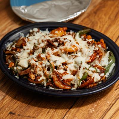 A bowl of shrimp fajitas topped with melted cheese.