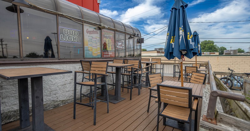 Outdoor patio area with tall black tables and dark blue umbrellas