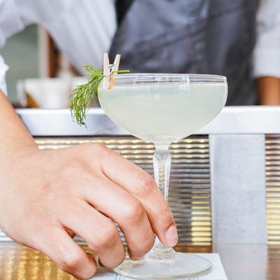 An employee putting a Dapper Dan cocktail on the table.