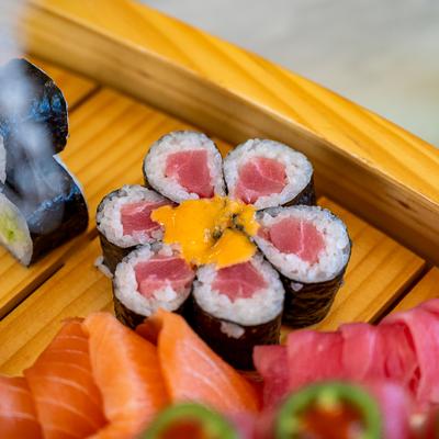 Sailboat platter featuring flower-shaped sushi roll alongside salmon and tuna sashimi.