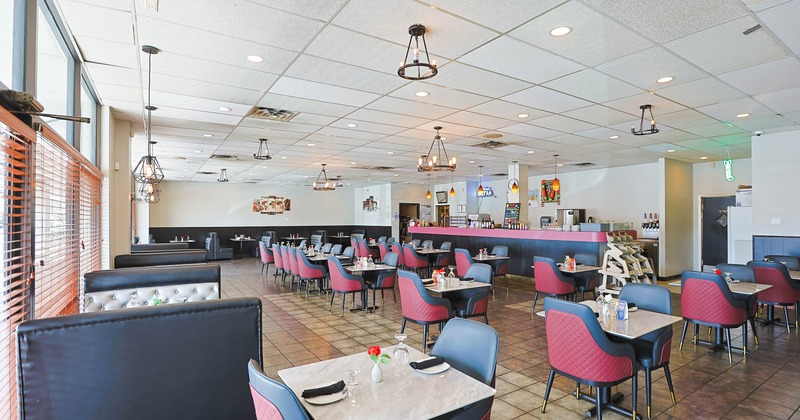 A modern restaurant interior with tiled floors, large windows, booth seating on the left