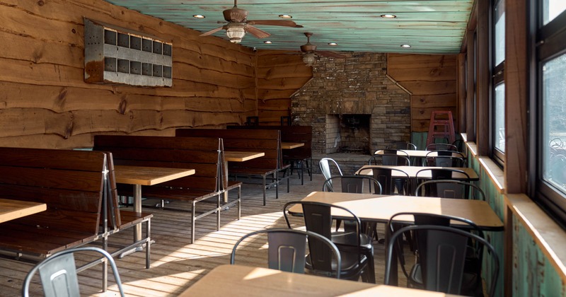 Interior, dining area, wooden booths, tables for four, stone fireplace in the back