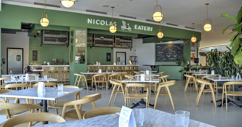 Spacious and cozy dining area with marble tables and wooden chairs, and a bar area