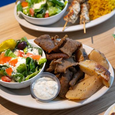 Gyro plate with roasted potatoes, Greek salad, and tzatziki sauce.
