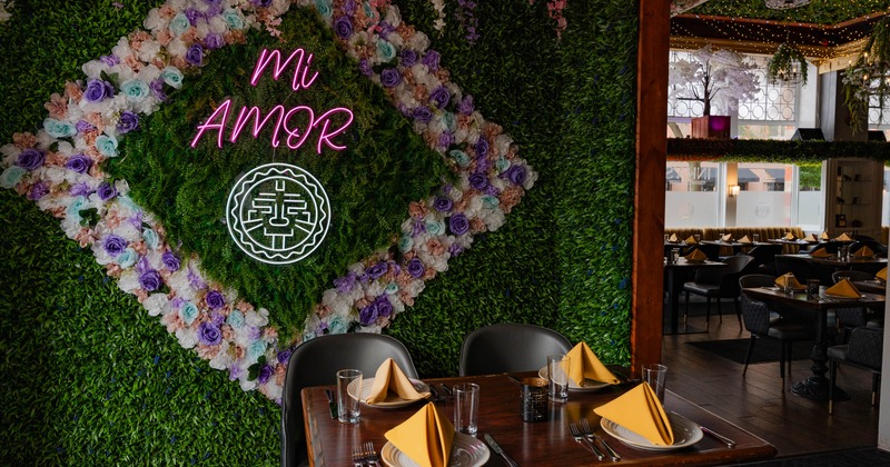Dining area featuring a decorative plant wall with neon text