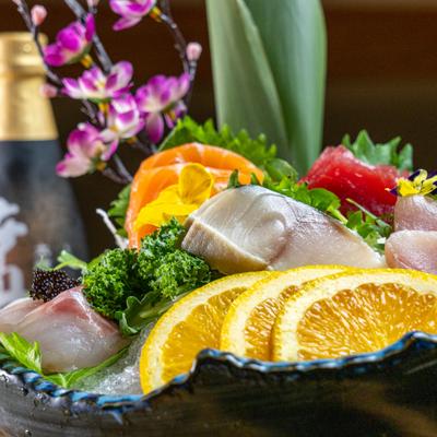 Sashimi deluxe platter served over crushed ice with various garnishes, close-up.
