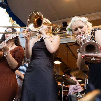 Three musicians playing brass instruments on a stage.