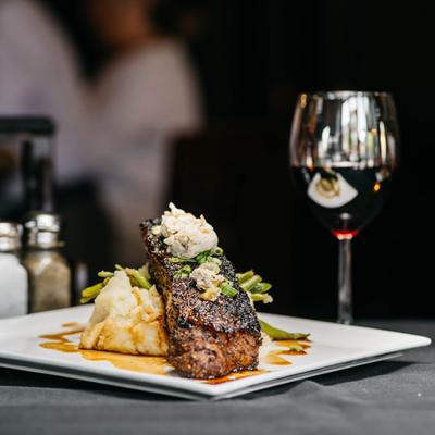 New York Strip Steak with mashed potatoes and green beans, accompanied with red wine