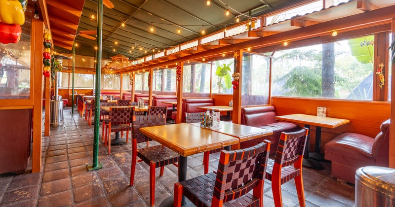 Interior, seating area, tables for four, booths, large windows, stone tile flooring