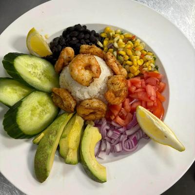 A vibrant plate featuring shrimp, rice, avocado, corn, and cucumbers.