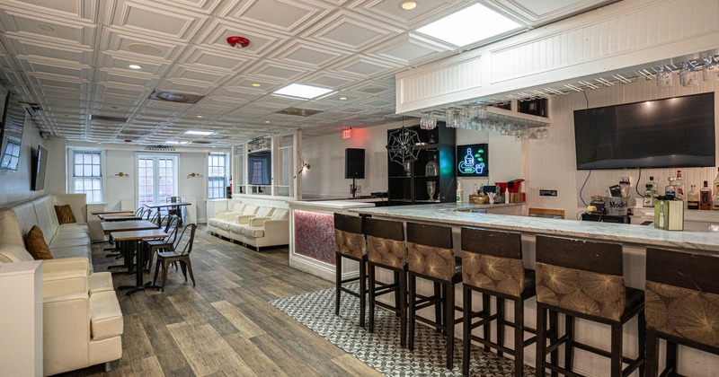 Modern interior - white booth seating, wooden tables, a marble-topped bar and dark wooden stools