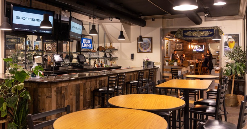 Interior, seating area, bar, separated dining area in the back, various plants, TVs