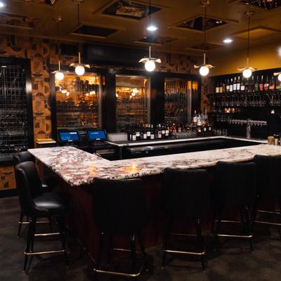 Bar area with bar seating, wine and hard liquor bottles, glassware