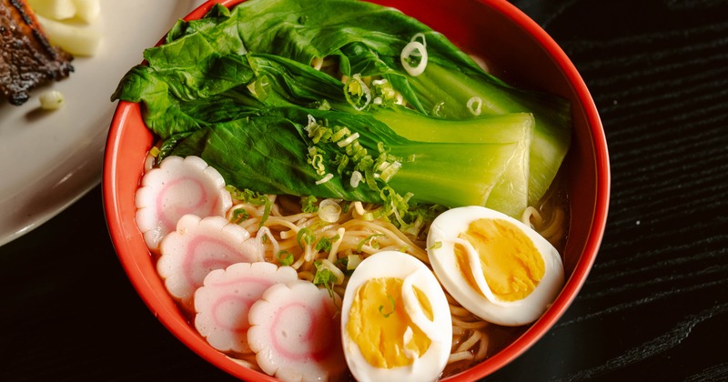 A bowl of Japanese ramen noodles served in a bright red bowl