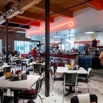 Retro diner interior with black-and-white chairs and red neon lights.