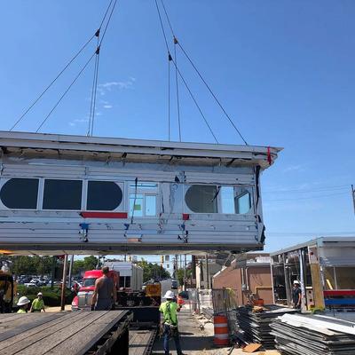 A crane lifts a house onto a construction site
