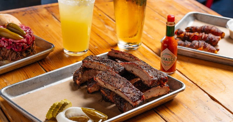 Pork spare ribs, served on a metal tray alongside other dishes and drinks