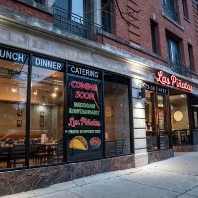 Las Piñatas restaurant exterior with large windows, illuminated signage, and a Coming Soon sign.