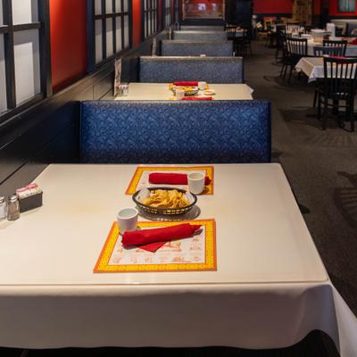 A row of dining booths, booth tables set with baskets of chips and place settings.