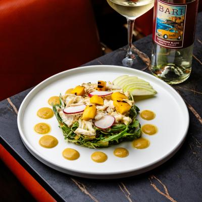 A crab and mango salad, accompanied by white wine.