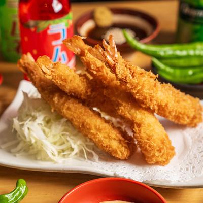 Crispy fried panko shrimp with shredded cabbage and green chilis in the background.
