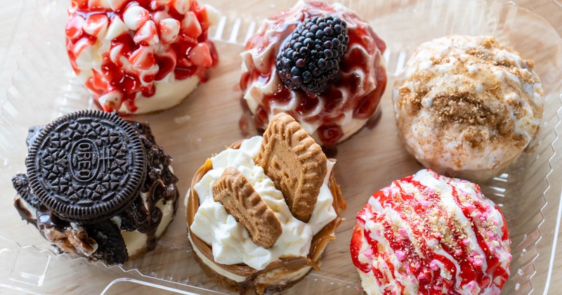 An assortment of mini cheesecakes in a clear plastic container