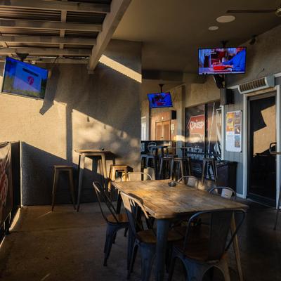 Covered outdoor seating with tables and TVs.