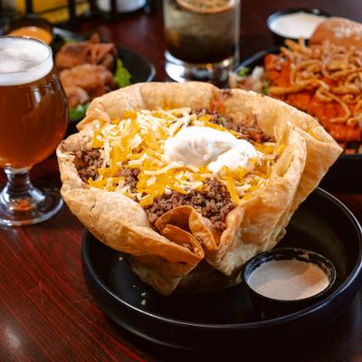 Taco salad in tortilla bowl with sour cream on the side.
