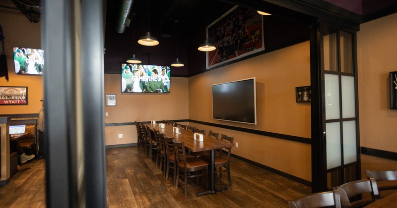 Interior, dining area, long wooden top table for eighteen, large TVs on the walls