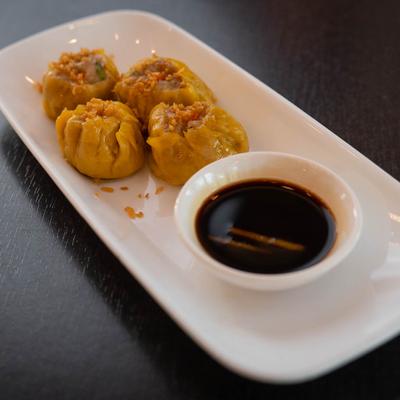 Steamed dumplings with a side of soy sauce.