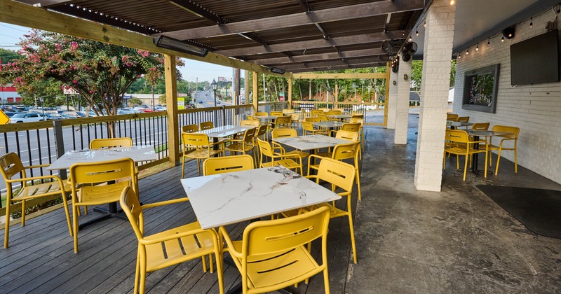 Outdoor patio with yellow chairs and white tables