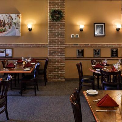 Dining room with brick accents, framed art and a blend of wooden tables and chairs.