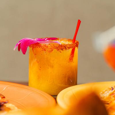 Spicy mango margarita with chili rim and orchid garnish.