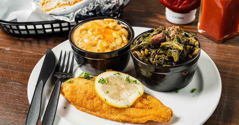 Fried fish served with creamy mac and cheese and collard greens