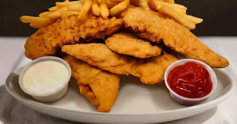 A pile of crispy chicken tenders and french fries with dipping sauces