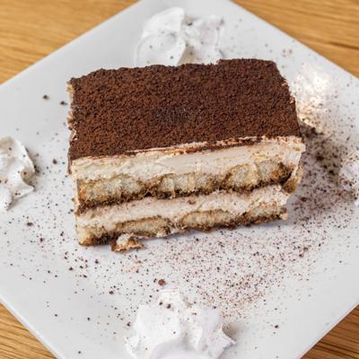 Tiramisu slice dusted with cocoa powder.