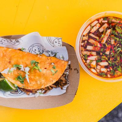 Birria taco topped with fresh cilantro, onions, and lime, served with consome.
