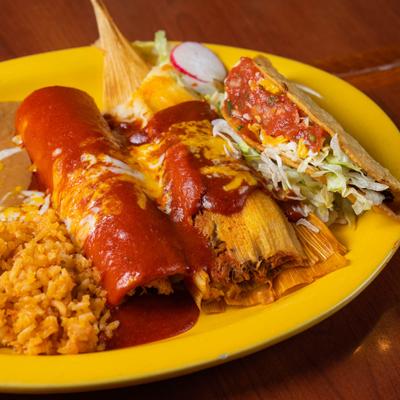 Combo plate with enchilada, tamale, taco, sides of rice and refried beans
