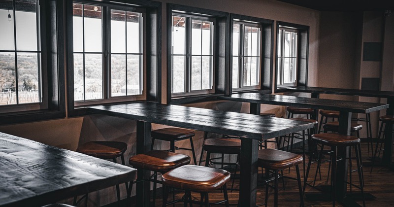 Interior, high seating area by the windows, wooden top tables with padded stools