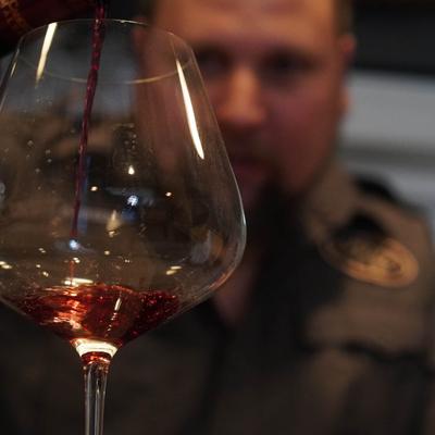 Bartender pouring a glass of red wine.