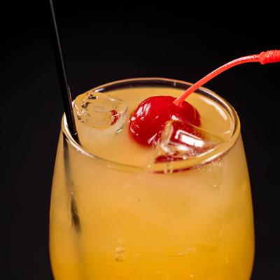 A yellow cocktail drink decorated with a cherry